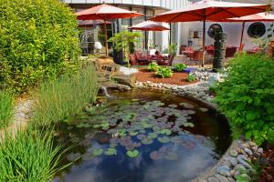 a pond with lilies in a yard with umbrellas at Hotel - Restaurant DAHM in Erpeldange