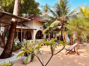 uma casa com uma cadeira e palmeiras em frente em Little Lagoon Hostel em Arugam Bay