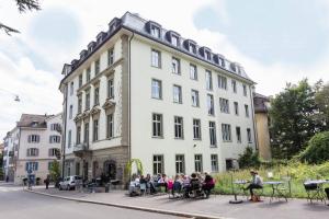 un grupo de personas sentadas fuera de un edificio en Design Hotel Plattenhof, en Zúrich