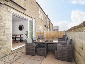 a patio with wicker chairs and a glass table at Wising Gill House in Harrogate