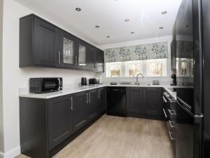 uma cozinha com armários pretos e um micro-ondas em Wising Gill House em Harrogate