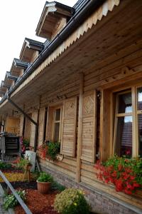 ein Holzhaus mit Blumen an der Seite in der Unterkunft Hotelik ze śniadaniami "KUR" Myszyniec-Kurpie in Myszyniec