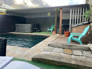 uma piscina com duas cadeiras azuis ao lado de uma casa em L'améthyste - Bungalow de charme em Cilaos