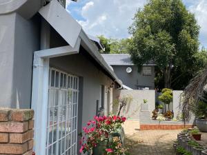 een huis met een witte deur met bloemen ervoor bij Ndzuti Guest House in Witbank