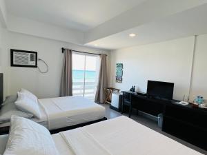 a hotel room with two beds and a desk and a window at Playa Azul Baler in Baler