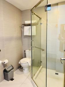 a bathroom with a toilet and a glass shower at Playa Azul Baler in Baler