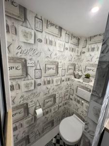 a bathroom with a toilet and a wall covered in pictures at Chambre D'hôte Villa Maurice in Étretat