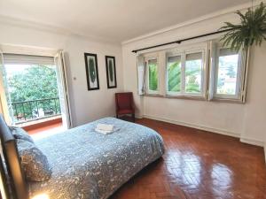 a bedroom with a bed and two windows at Botanique Guesthouse in Cascais