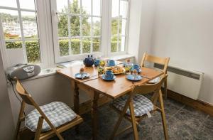 a wooden table with two chairs and a meal on it at Shipwrights - Views across the Marina and River Dart, perfect bolthole in Kingswear