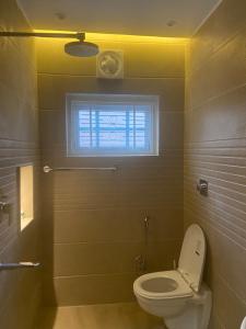 a bathroom with a toilet and a window at BELLE VUE COTTAGES in Kūd