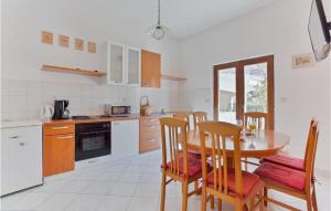a kitchen with a table and chairs and a kitchen with white appliances at Amazing Apartment In Petrcane With Wifi in Petrcane
