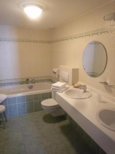 a bathroom with a tub and a toilet and a sink at Le Château de Rendeux in Rendeux