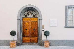 une porte en bois sur un bâtiment blanc avec deux plantes dans l'établissement Palazzo Feroci - Residenza d'epoca, à Pise