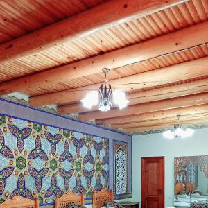 a dining room with a wooden ceiling with a tile wall at Koh-i-noor in Bukhara