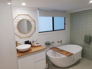a bathroom with a tub and a sink and a mirror at Maunder Cottage Aldinga Township in Aldinga +39 photos