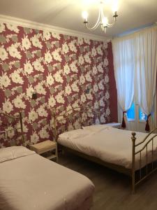 1 dormitorio con 2 camas y pared de flores en Hôtel Emilie, en Royan