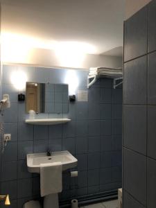 baño con lavabo blanco y azulejos azules en Hôtel Emilie, en Royan