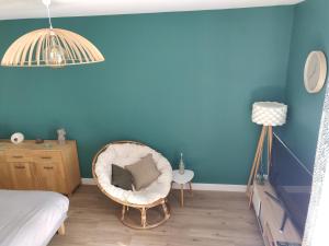 a bedroom with a chair and a blue wall at Scandinave - proche gare & centre-ville - stationnement - cour intérieure table & chaises in Saint-Brieuc