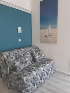 a couch sitting in a living room with a painting at Hôtel Aunis-Saintonge in Royan
