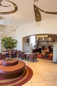 - un hall avec une table, des chaises et un arbre dans l'établissement Hôtel François Premier Cognac Centre, à Cognac