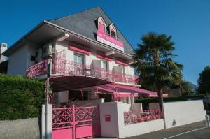 un bâtiment rose avec un palmier devant lui dans l'établissement Au Primerose Hôtel, à Argelès-Gazost
