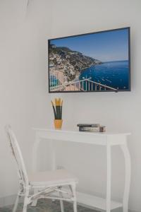 a white desk with a white chair and a tv on a wall at Villa Nettuno in Positano