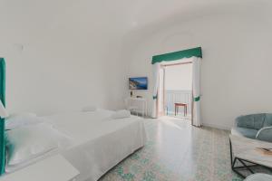 a white bedroom with a bed and a couch at Villa Nettuno in Positano