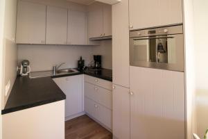 une cuisine avec des armoires blanches et un évier dans l'établissement Sunshine, Zeedijk 335 , Studio, nieuw Westende Bad, à Middelkerke
