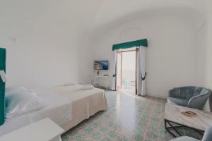 a white bedroom with a bed and a chair at Villa Nettuno in Positano