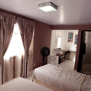 a bedroom with two beds and a window at Natal Aconchegante in Natal