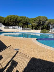 a large swimming pool with blue water at Studio vue port, parking privé, terrasse, clim in Le Grau-du-Roi