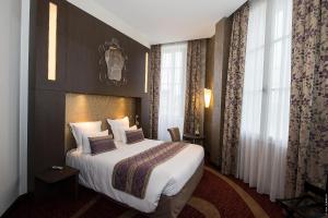 um quarto de hotel com uma cama e uma grande janela em Hôtel François Premier Cognac Centre em Cognac