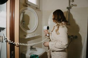 una mujer de pie en un baño que se seca el pelo en Hotel Flamengo Riccione, en Riccione