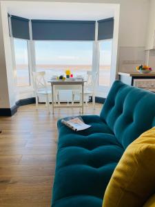 a living room with a blue couch and a table at TYME Coastal Retreats - 1 and 2 Bedroom in Cleethorpes