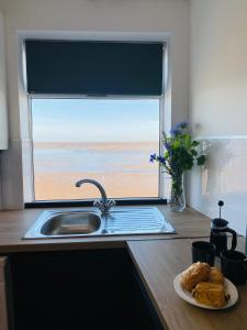 a kitchen with a sink and a window with a plate of bread at TYME Coastal Retreats - 1 and 2 Bedroom in Cleethorpes