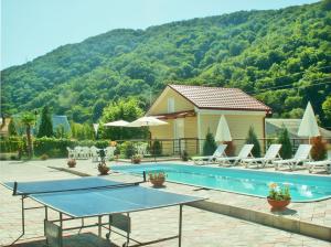a swimming pool with chairs and a house and a mountain at Solnechniy Guest house in Olginka
