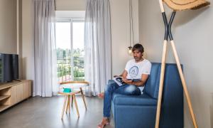 um homem sentado numa cadeira azul numa sala de estar em Apartamentos Dena em Coirón