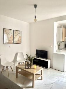 ein Wohnzimmer mit einem Tisch, Stühlen und einem TV in der Unterkunft 1.1 Apartamentos Arguiñan in Córdoba