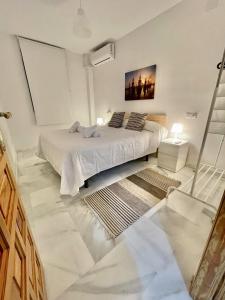 1 dormitorio blanco con 1 cama y una pintura en la pared en Bj. A Apartamentos Arguiñan, en Córdoba