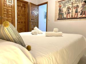 2 camas en una habitación con sábanas blancas y toallas en Bj. A Apartamentos Arguiñan, en Córdoba