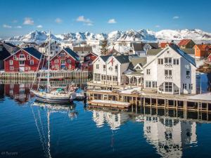 a harbor with houses and a boat in the water at Villa Bryggekanten - by Classic Norway Hotels in Henningsvær