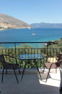 een tafel en stoelen op een balkon met uitzicht op het water bij Ballas Apartments in Ayia Evfimia