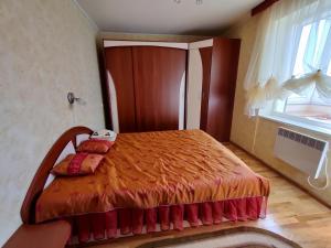 a bedroom with a bed with an orange bedspread and a window at Prie Masčio ežero in Telšiai