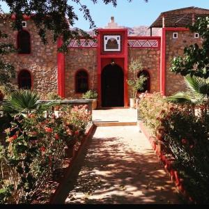 un bâtiment avec une porte rouge et une horloge. dans l'établissement Villa Siliya maga Cœur vallée amlen tafraout, à Tafraout