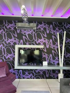 uma sala de estar com televisão e uma parede roxa em Purple Villa em Paralimni