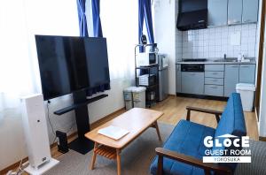 ein Wohnzimmer mit einem TV und einem blauen Sofa in der Unterkunft GLOCE 横須賀 ゲストルーム 横須賀海軍基地 l Yokosuka Guest Room at NAVY BASE in Yokosuka
