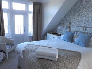 a bedroom with a large white bed with blue pillows at Breakers Bed and Breakfast in Eastbourne