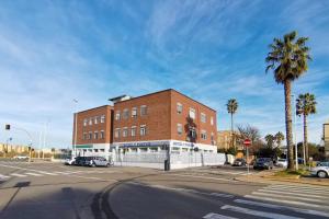 an intersection with a brick building and a palm tree at Hotel Poetto in Cagliari