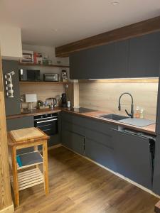 a kitchen with gray cabinets and a sink and a table at Maison Stabatio Appartement Margot in Le Monêtier-les-Bains