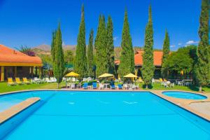 a pool with tables and chairs and trees at Hotel Los Parrales in Tarija